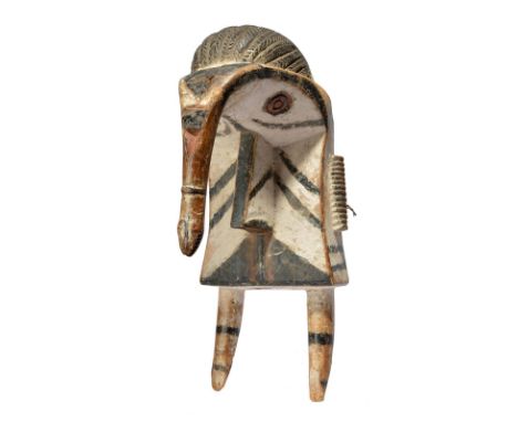 An Izzi elephant mask Nigeria with a large mask to the back with filed teeth and with a serpent head trunk, having white, bla