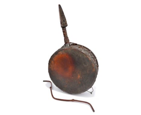 A Nepalese Shaman's drum with a carved handle, vellum and fibre and with curved stick beater, 60cm long. (2)