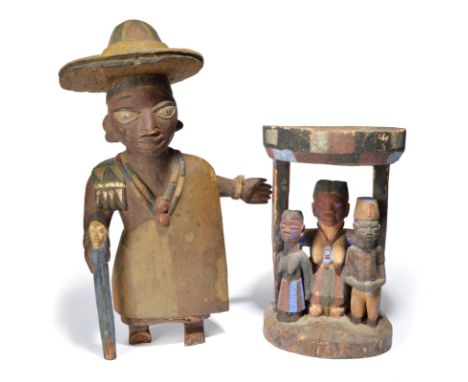 A Yoruba standing figure Nigeria wearing a large rimmed hat and holding a staff, with painted decoration, 67cm high, and a Yo