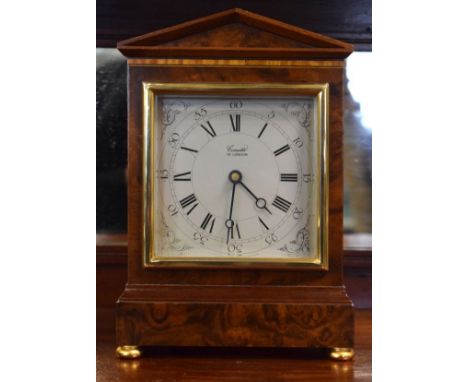Mahogany and burrwood cased mantel clock by Comitti of London, silvered dial with Roman and Arabic numerals, standing on bras