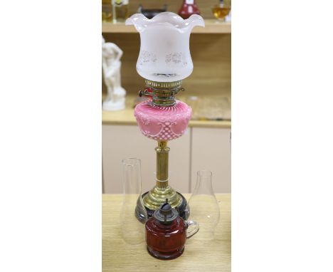 A late Victorian brass oil lamp with pink glass reservoir and a cranberry oil lamp