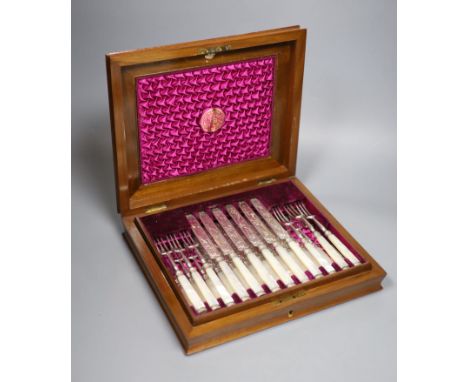 A Victorian walnut cased set of twelve pairs of mother of pearl handled dessert eaters, the blades and forks engraved with as