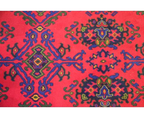 A wool carpet, worked with a foliate design against a red ground, 370cm x 366cm