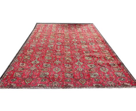 A Persian hand woven wool carpet, worked with an all-over floral design in rose against a red ground, 300cm x 210cm 