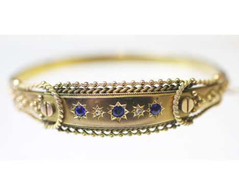 An Edwardian 9ct yellow gold bangle, Birmingham 1907, the hinged bangle set with blue stones and rose cut diamonds, within ro