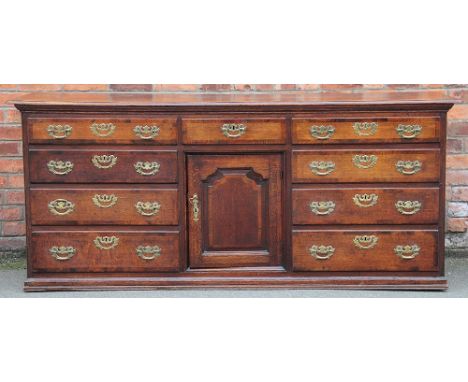 A George III oak and walnut cross banded dresser, the three plank top with rounded corners and a moulded edge above a central