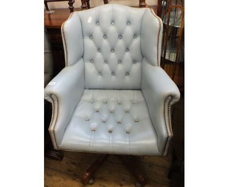 A sky blue leather button back swivel armchair