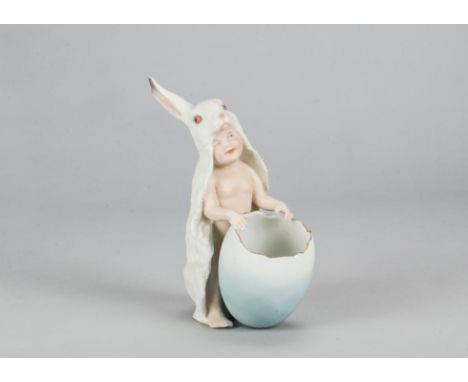 A rare Gebruder Heubach baby in rabbit skin, standing holding an egg shaped posy vase, the white rabbit skin draped from head