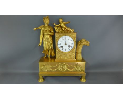 A gilt metal cased mantle clock figures to top with applied decoration, white enamel dial with Roman numerals to chapter ring