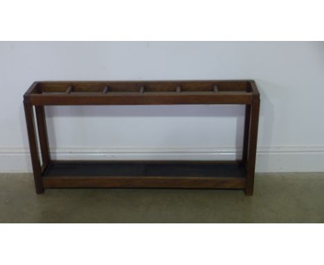 A single row stick stand with six compartments, drip tray below, raised on square supports - Height 53cm x 109cm x 20cm 