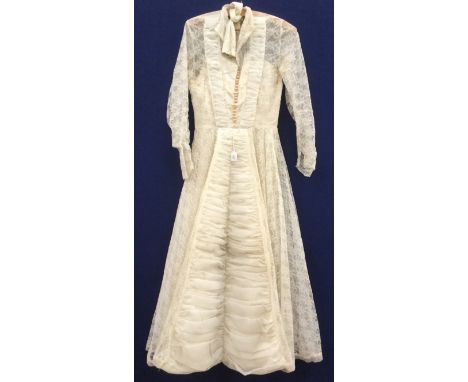  A 1950's Chiffon and lace wedding dress. The chiffon is ruched down the front to the hem. Pearl buttons adorn the bodice (Di