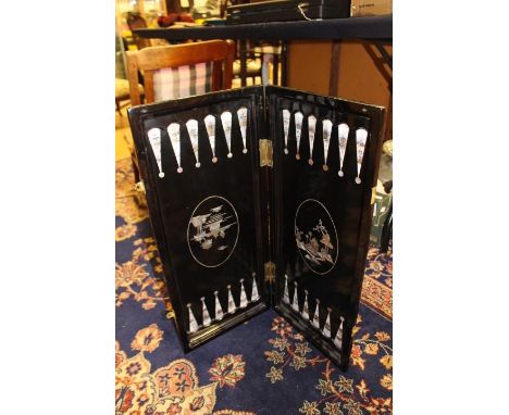 An early 20th Century Chinese export black lacquer folding games board, inset and engraved mother of pearl decoration, 64cm b
