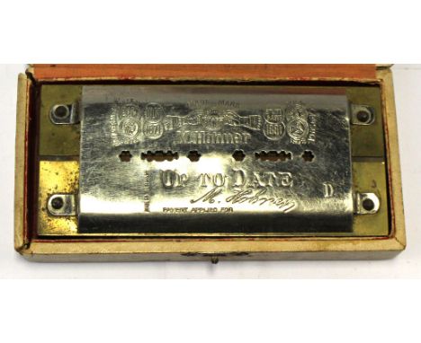  An early 20th Century harmonica in original box, embossed with makers name, the box has a red silk lining