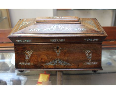 A Regency rosewood and mother of pearl inlaid sarcophagus shaped twin handled tea caddy, with two lidded canisters centered b