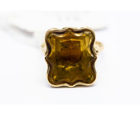 A Georgian style 18ct. yellow gold and citrine seal ring, having large table cut shaped citrine in raised scroll work mount w