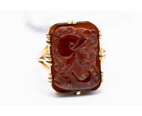 A gold and garnet cameo ring, carved with classical Roman figures, the cameo approx. 13mm x 19mm, claw set, ring size P, tota