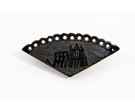 A Victorian jet "fan" shaped brooch, having carved panel depicting Whitby Abbey ruins, with circular pierced upper border and
