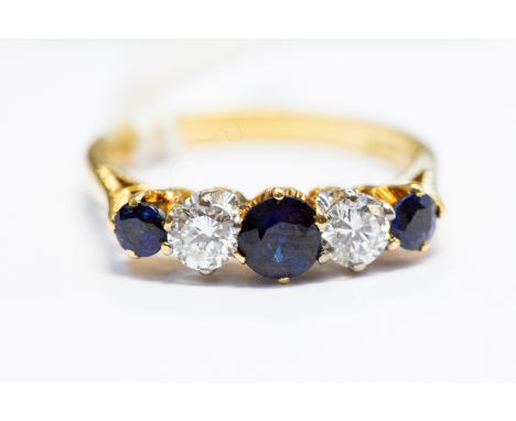 A sapphire and diamond five-stone 18ct gold ring, the central round-cut sapphire approx. 4.6mm, two round brilliant-cut diamo