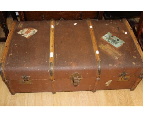 An early 20th Century canvas and wood bound travelling trunk, complete with original travelling labels