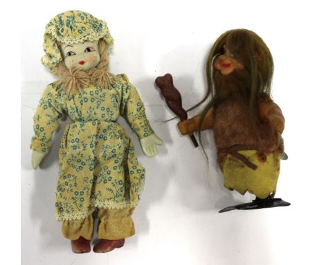 A tin plate wind up figure of a cave man having composite head and arms; with a soft bodied doll, having ceramic head, hands 