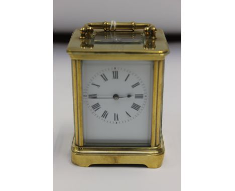 A brass carriage clock, of traditional rectangular form, with swing carry handle and white enamel Roman numeral chapter ring,