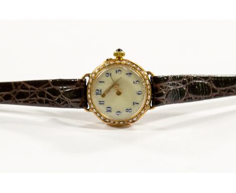 A circa 1920's lady's 18kt gold wristwatch, 2.5cm circular white dial with seed pearl set bezel, blue Arabic numerals, sapphi