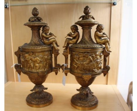 A pair of mid 19th Century urns, circa 1840, cast metal, gilded, decorated with cherubs and grapes, the finial are grapes wit