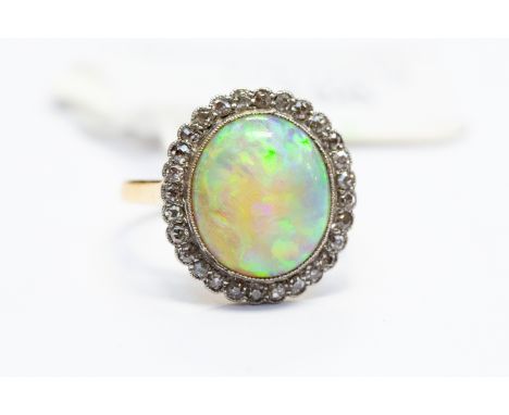 An Edwardian opal and diamond ring, comprising a large solid opal, approx 3.75 ct, displaying yellow, green, purples, with a 