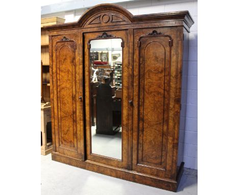 A good Aesthetics figured walnut triple wardrobe, the central mirrored door surmounted by a secular pediment is flanked by tw