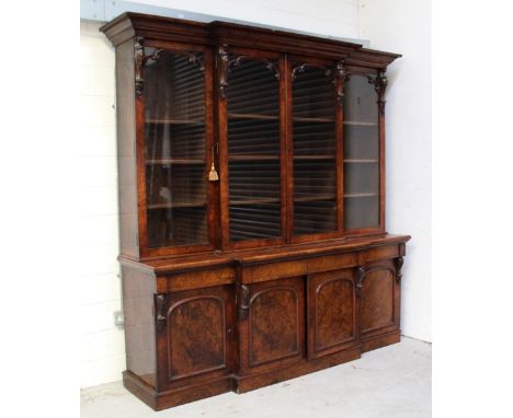 A mid-19th century burr walnut break-front elevated bookcase, the flared cornice surmounting four glazed doors with scrolling