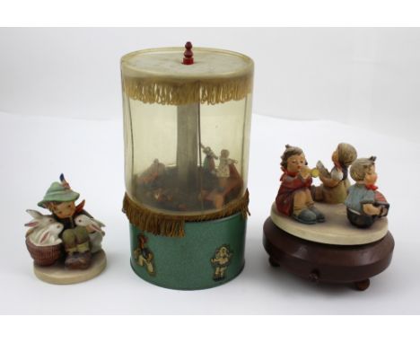 A Hummel music box with three seated children, one playing the trumpet, one with a squeeze box and a little girl with song sh