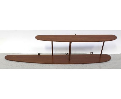 A 1970s designer teak wall shelf unit comprising two shaped planks united by four bobbin-turned supports, width 114cm.