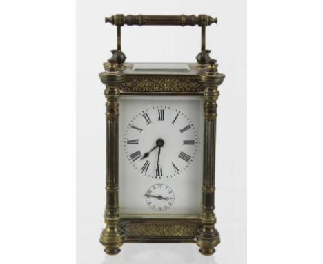 A late 19th century brass carriage clock with fluted pilaster columns and blind fretwork frieze, enamelled dial set with Roma