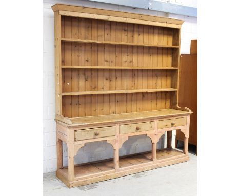 An early 20th century pine dresser of large proportions, three shelf plate rack over three frieze drawers to lower pot shelf,