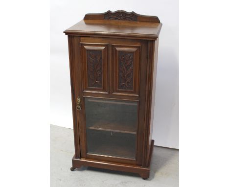 A late 19th century walnut music cabinet with relief carved gallery back supporting a single door with twin carved panels to 