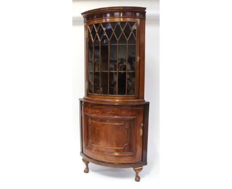 A 19th century mahogany two-tier bow-front corner cabinet, the upper glazed section with beaded bars opens to reveal two fixe