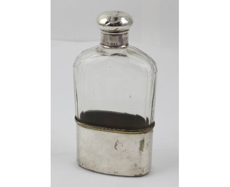 A faceted cut glass hip flask with hallmarked silver lid and with silver-plated brass sleeve cup, height 17cm.