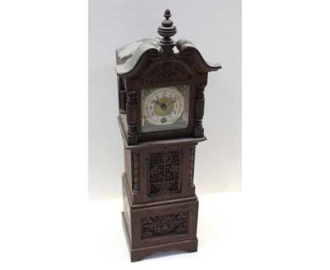 An oak-cased carved mantel clock in the form of a clock tower, gilded and silvered dial set with Arabic numerals, height 41cm