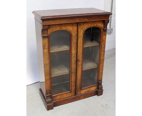 A good Victorian Aesthetic period burr walnut double-fronted pier cabinet, each door with arched glass panel opening to velve