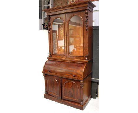 A Victorian mahogany cylinder roll bureau bookcase, elevated bookcase section with flared cornice above twin arch panel glass