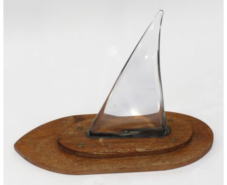 An abstract sculptural glass model of a yacht on a stepped wooden base in the form of a boat with a glass sculptured sail, le