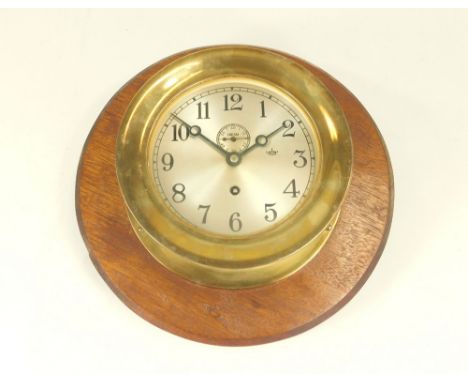 BULKHEAD CLOCK. A brass bulkhead clock, with seconds dial marked 'Chelsea'. Now mounted on mahogany. Diameter 18.3cm.