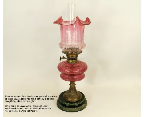 OIL LAMP.A Victorian oil lamp with cranberry glass fount, matching cranberry shade & green glazed ceramic base. Height 59cm. 