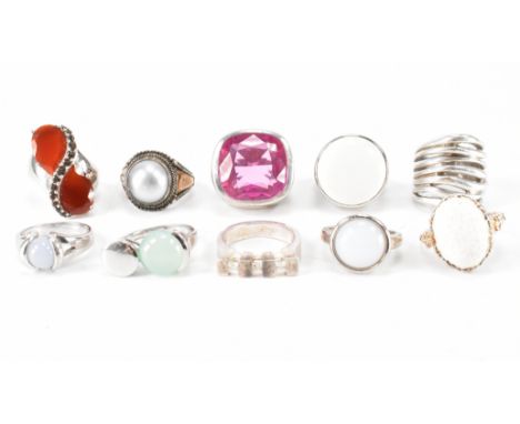 A group of ten silver stone set rings. The lot to include a faux pearl ring, large synthetic ruby dress ring, red stone cross