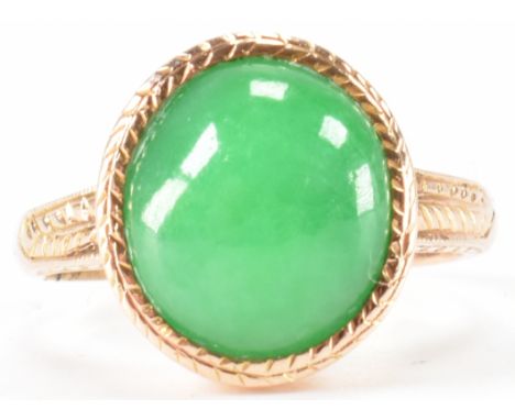 A vintage gold and jade cabochon ring. The ring being set with an oval polished jade cabochon with incised detailing to the h