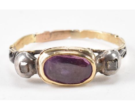 A George III antique gold, diamond and ruby ring. The ring being set with an oval cut ruby in a rub over setting flanked by t