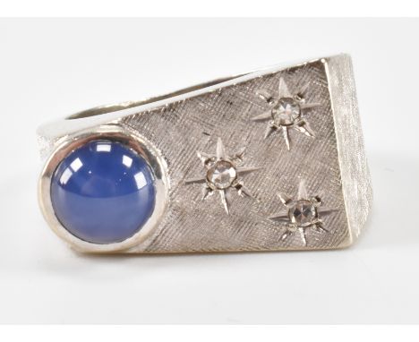 A white gold diamond and star sapphire dress ring. The ring an offset star sapphire to the head with a trio of round cut diam