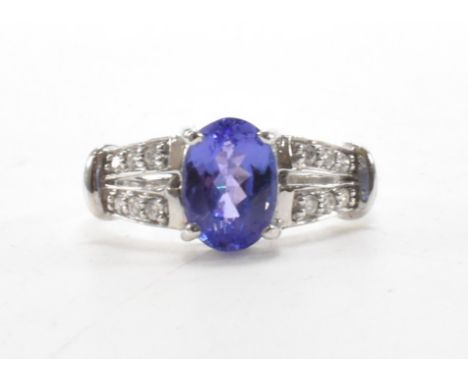 A hallmarked 18ct gold tanzanite and diamond ring. The ring set with an oval mixed cut tanzanite, measuring 3.9mm x 6.1mm x 4