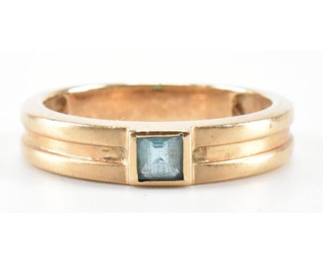 A hallmarked 9ct gold and blue topaz band ring. The ring being set with a square cut blue topaz on banded shoulders. Hallmark