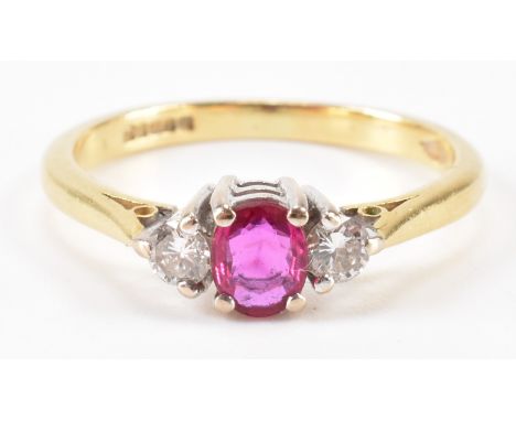 A hallmarked 18ct gold ruby and diamond three stone ring. The ring being set with an oval cut ruby flanked by two round cut d